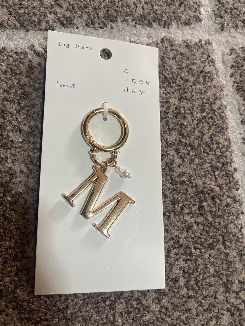 A New Day Letter M Bag Charm (Category: Charms) located in Pasig City. Submitted by jundbaptist21 (Listing ID 1427500745, Image 1). Description: Bag charm from A New Day features the letter "M" in gold. It includes a small pearl accent and a clasp for easy attachment. The original price tag is still attached, showing a price of $10.00. Perfect for adding a personalized touch to your bag or keys. From U.S.
