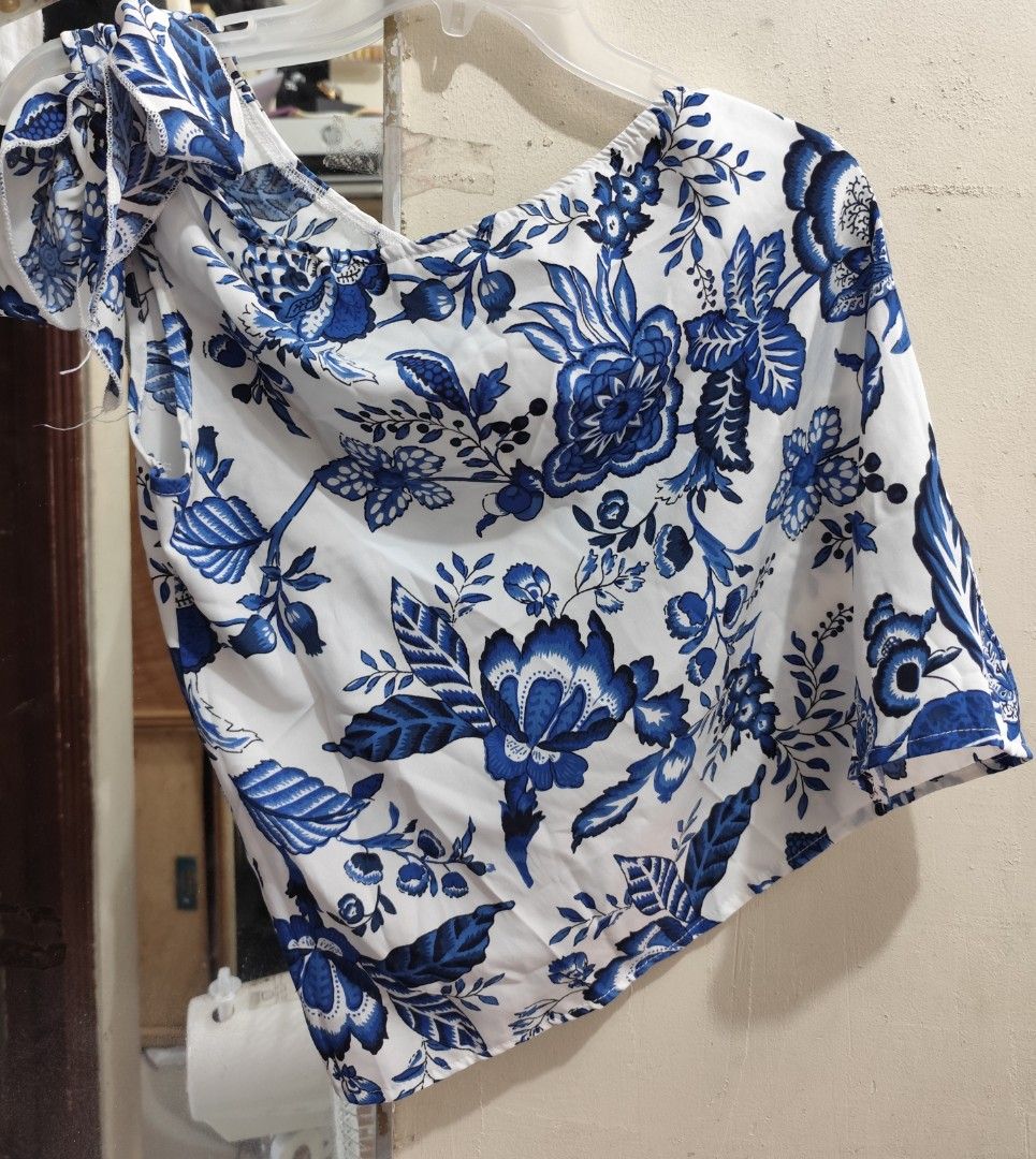 Blue Floral Off-Shoulder Top (Category: Blouses) located in Quezon City. Submitted by melsc (Listing ID 1427544738, Image 1). Description: Can Fit up to MEDIUM USED ONLY ONCE Off-shoulder top features a beautiful blue floral pattern on a white background. It has a unique asymmetrical design. The top is made of a lightweight fabric, perfect for warm weather..