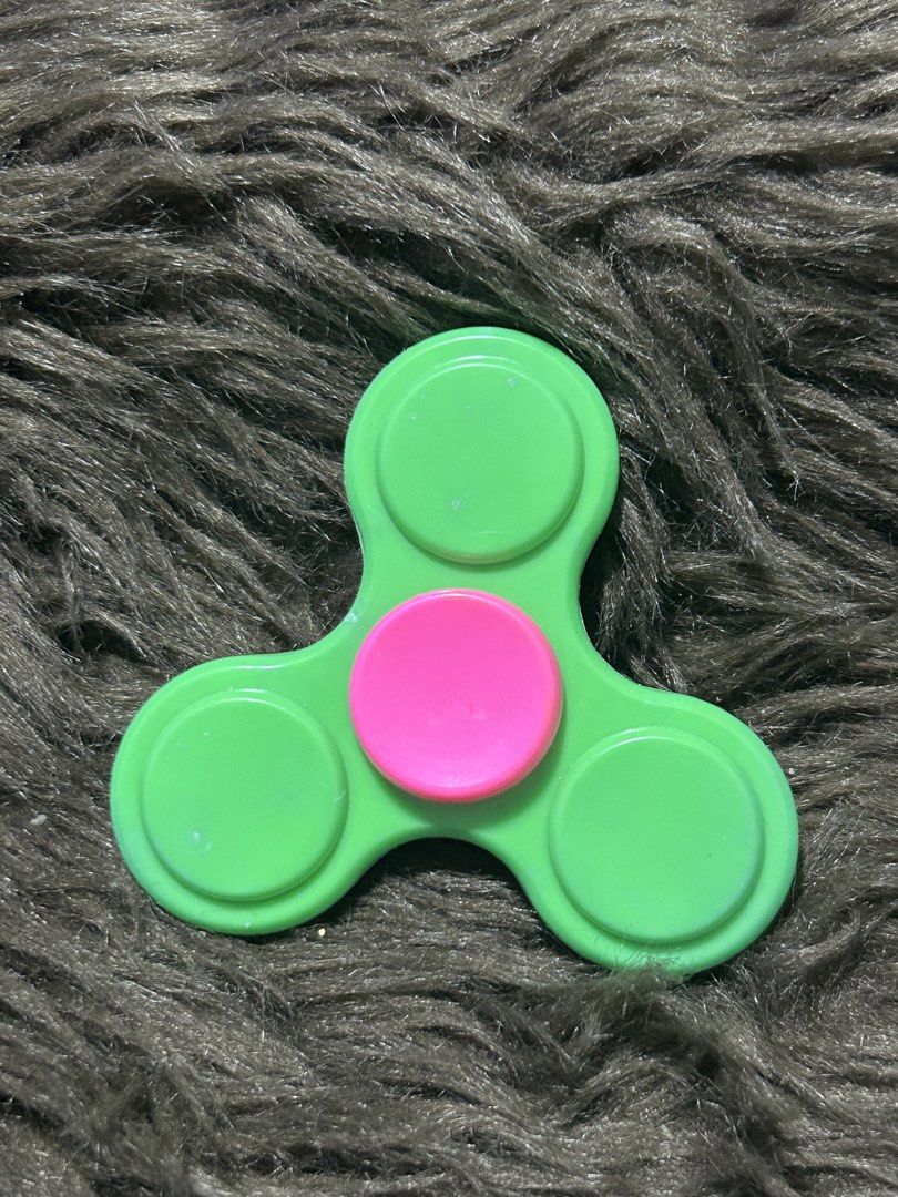 Bo21Green and Pink Fidget Spinner (Category: Action & Battle Toys) located in Angeles City. Submitted by zyeplustradings (Listing ID 1427572968, Image 2). Description: Fidget spinner features a vibrant green body with a pink center. It has a three-leaf design with rounded edges. The spinner is designed to be held in the hand and spun for entertainment or stress relief. It is a simple, classic design..