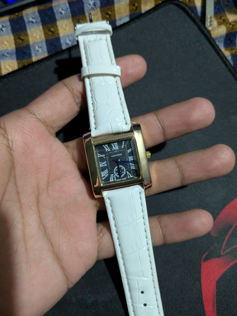 Cartier Tank Watch with White Strap (Category: Luxury Watches) located in Manila. Submitted by jaydrenn (Listing ID 1427525250, Image 1). Description: Elegant Cartier Tank watch featuring a rectangular gold-toned case and a black dial with Roman numeral hour markers. It has a white leather strap with a crocodile pattern. The watch has a stainless steel back. The watch is a classic design, suitable for both casual and formal occasions..