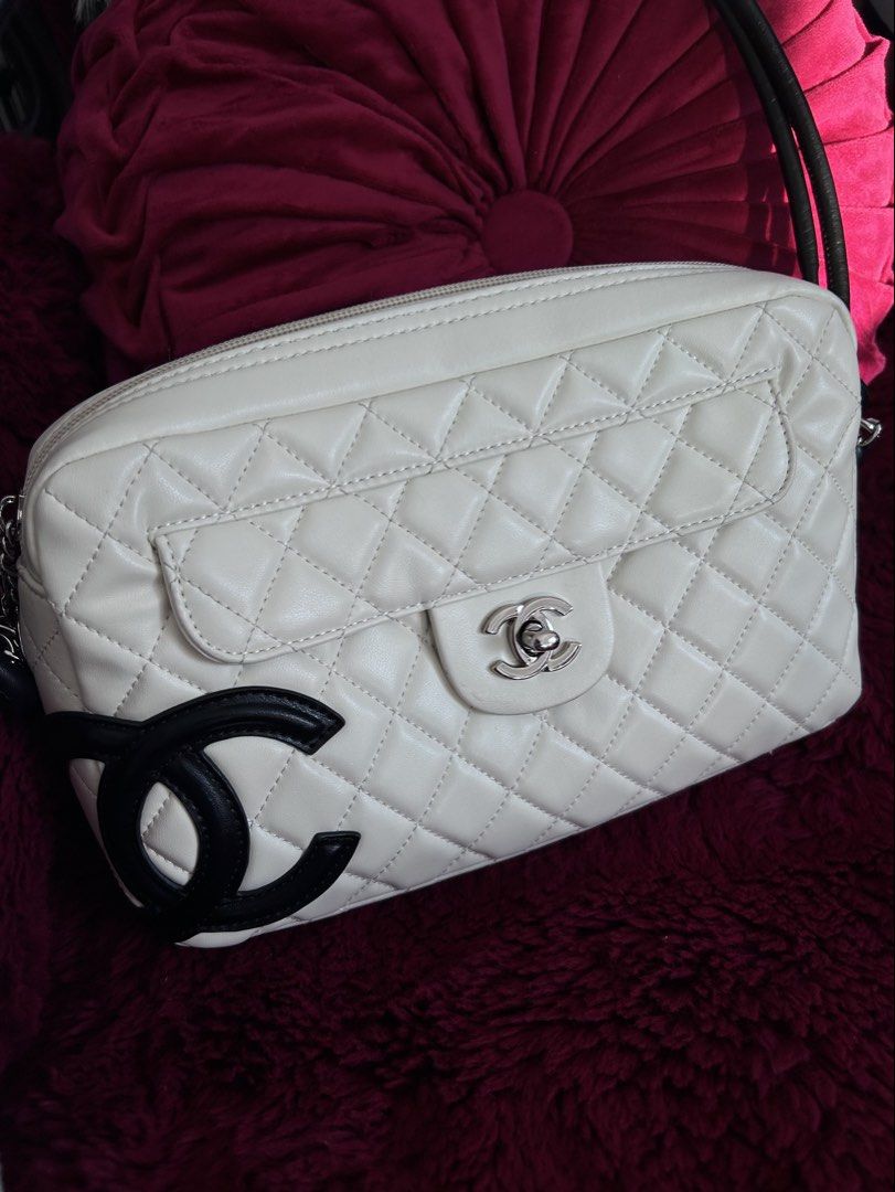 Chanel White Cambon Camera bag (Category: Luxury Bags & Wallets) located in San Juan, La Union. Submitted by soulmourn (Listing ID 1427547697, Image 2). Description: Chanel camera bag features a white quilted leather exterior with a black logo. It has a silver-tone zipper and chain detail. The interior is lined with a dark fabric and includes a zippered pocket. The bag has a black leather strap..