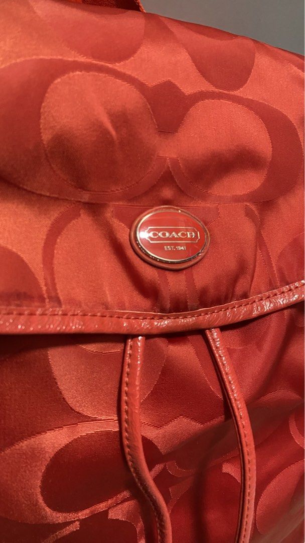 Coach Signature Backpack (Category: Luxury Bags & Wallets) located in Manila. Submitted by owabaet12 (Listing ID 1427633508, Image 2). Description: Coach backpack features a signature pattern in a vibrant orange color. It has a drawstring closure and adjustable straps. The backpack includes a Coach logo emblem. The design includes a flap closure and a small leather tag..