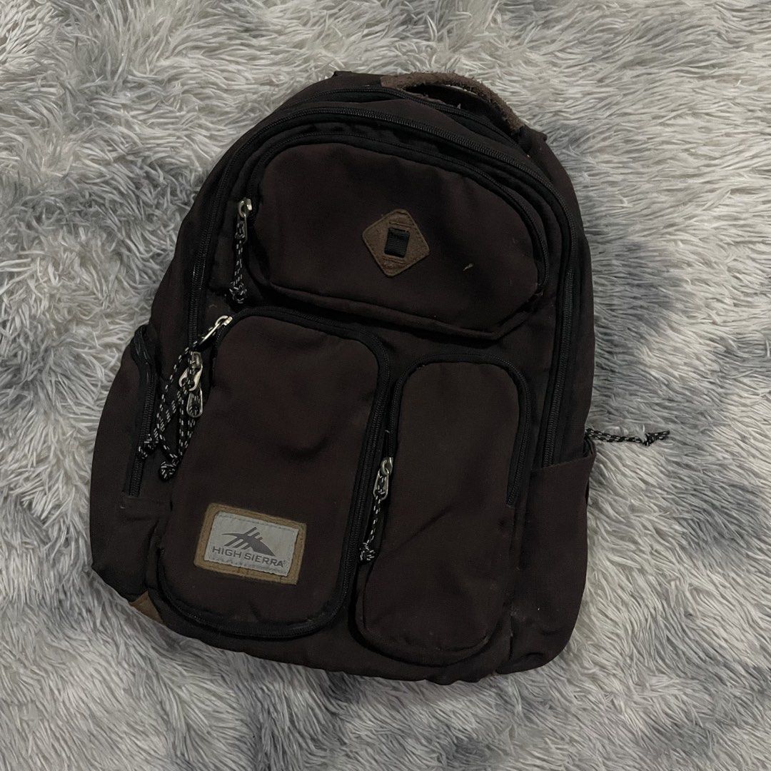 High Sierra Backpack (Category: Backpacks) located in Trece Martires City. Submitted by zav_vinny (Listing ID 1427602717, Image 2). Description: Durable High Sierra backpack in brown. Features multiple compartments, including two front pockets with zipper closures. The main compartment has a zipper closure and a padded back panel. The High Sierra logo is visible on the front..