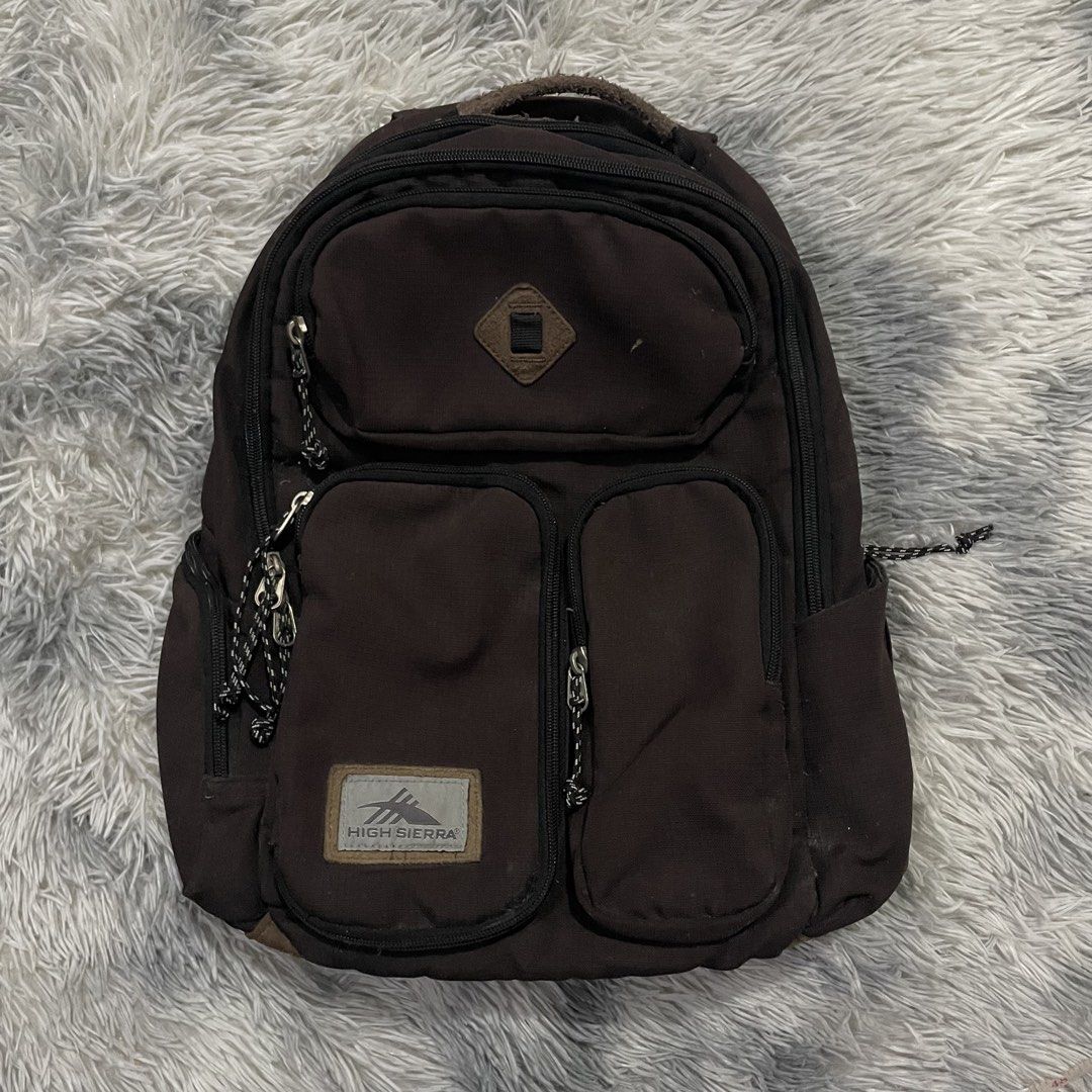 High Sierra Backpack (Category: Backpacks) located in Trece Martires City. Submitted by zav_vinny (Listing ID 1427602717, Image 1). Description: Durable High Sierra backpack in brown. Features multiple compartments, including two front pockets with zipper closures. The main compartment has a zipper closure and a padded back panel. The High Sierra logo is visible on the front..