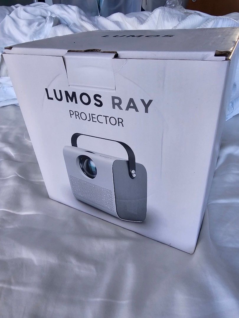 Lumos Ray Projector - Basic (Category: Projectors) located in Singapore. Submitted by jot161921 (Listing ID 1427488771, Image 2). Description: Lumos Ray projector. Features multiple input ports including HDMI, USB, and TF card. Compact and portable design. Perfect for home entertainment or presentations. The LUMOS RAY Smart Projector is superior for home entertainment, featuring a built-in Android OS with Wi-Fi, native Netflix/YouTube, Bluetooth,