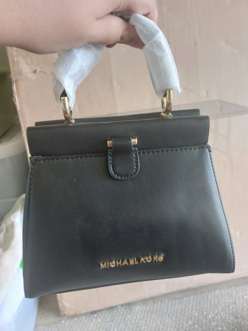 Michael Kors Black Handbag with Lock (Category: Luxury Bags & Wallets) located in Malaybalay. Submitted by mags_sofia (Listing ID 1427591712, Image 2). Description: Dimensions: L: 17.5", W: 4.5", H: 10.5" Material: - leatherette exterior and polyester interior - gold brass hardware - includes dry bag & strap Compartment: - first main compartment has one zipped pocket - second main compartment has one slot Signs of Wear: - leather edges are worn o