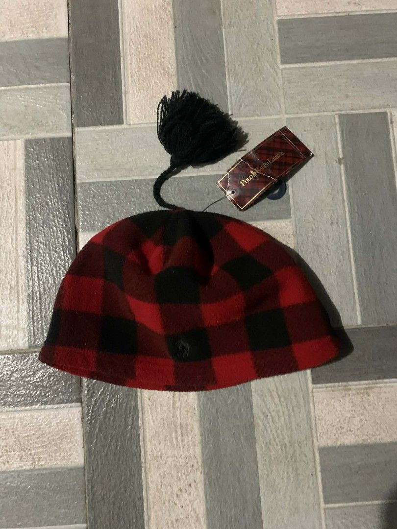 Polo Ralph Lauren Plaid Beanie (Category: Hats & Beanies) located in Cordova. Submitted by statanthrifts (Listing ID 1427598642, Image 1). Description: Authentic Polo Ralph Lauren beanie in a classic red and black plaid pattern. Features a black pom-pom and the Polo Ralph Lauren logo. The tag indicates the size is OS (8-20). Made of 100% polyester. Includes original tags. A stylish and warm accessory for the colder months..