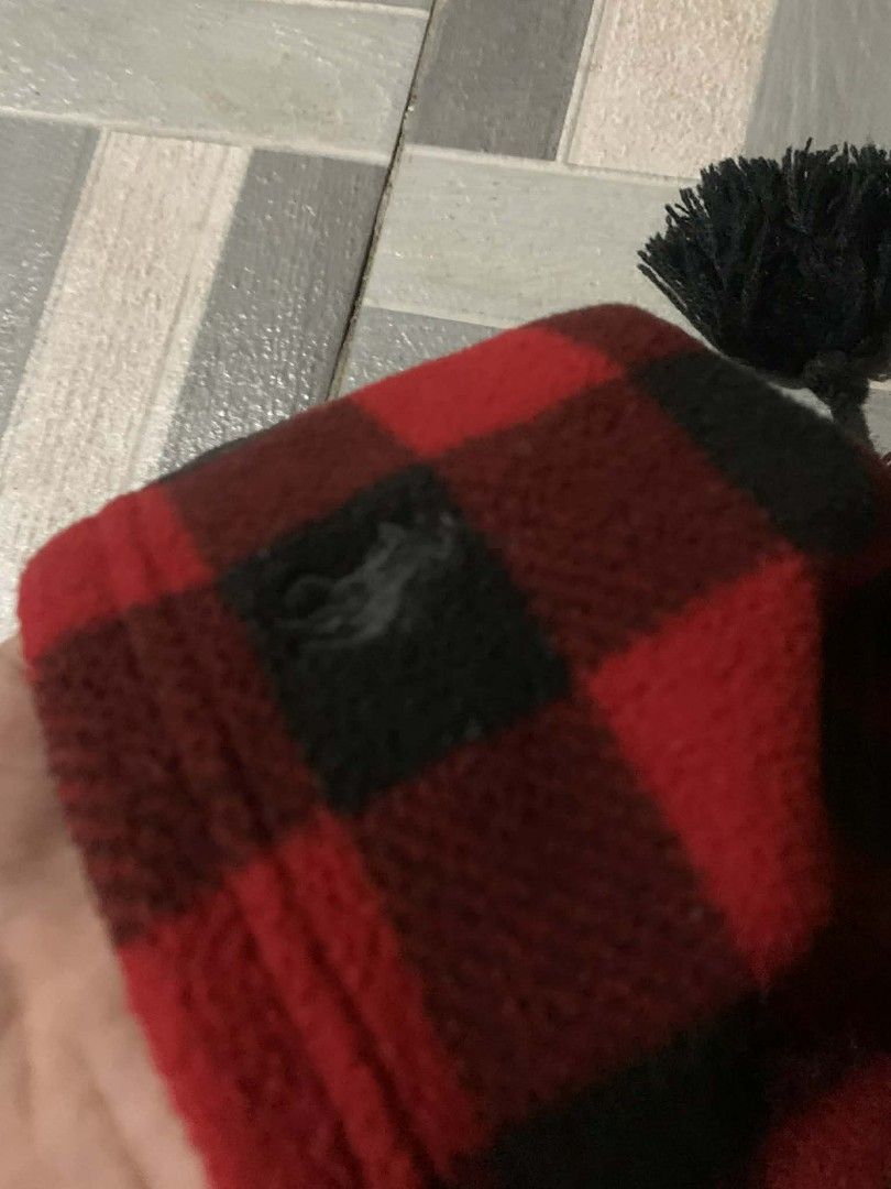 Polo Ralph Lauren Plaid Beanie (Category: Hats & Beanies) located in Cordova. Submitted by statanthrifts (Listing ID 1427598642, Image 2). Description: Authentic Polo Ralph Lauren beanie in a classic red and black plaid pattern. Features a black pom-pom and the Polo Ralph Lauren logo. The tag indicates the size is OS (8-20). Made of 100% polyester. Includes original tags. A stylish and warm accessory for the colder months..