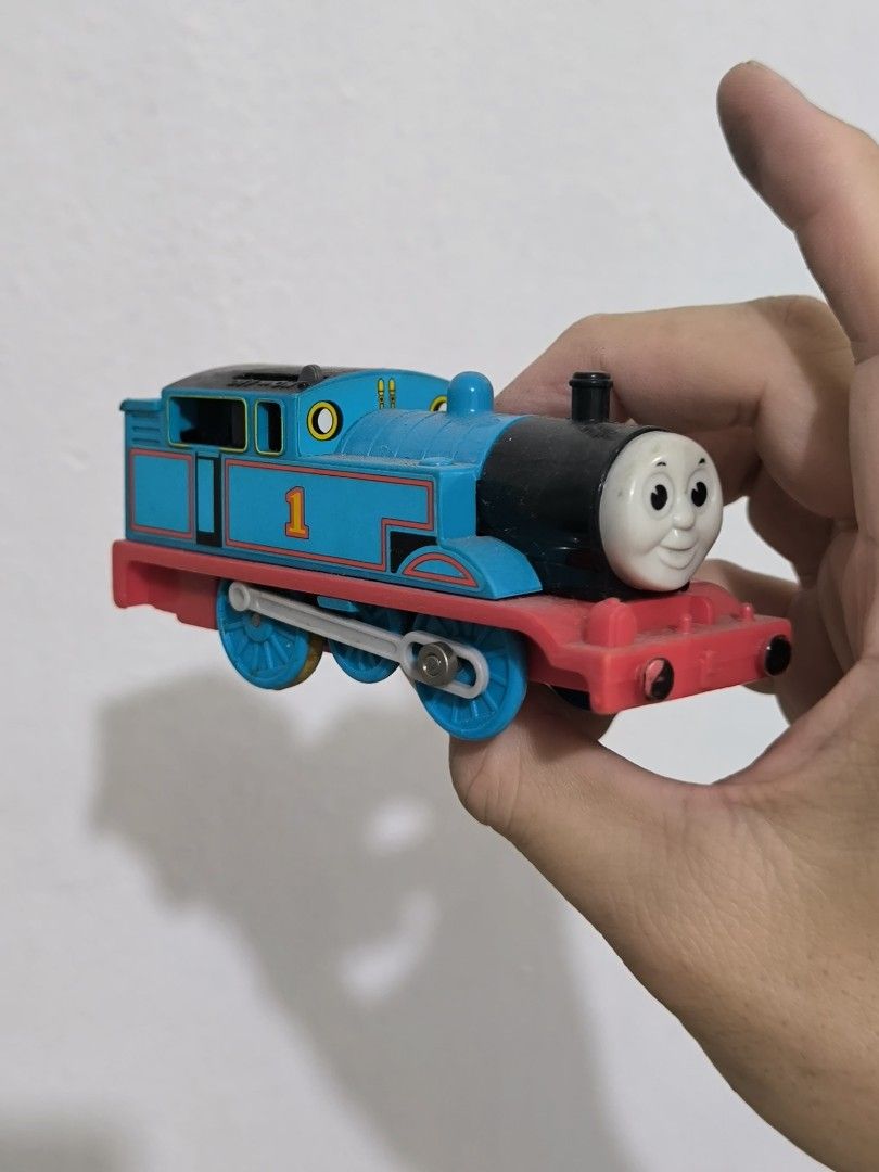 Tomica Thomas the Tank Engine Train (Category: Vehicle & Diecast Models) located in Angeles City. Submitted by yellowbrickstore (Listing ID 1427507933, Image 1). Description: Tomica Thomas the Tank diecast Engine toy train. It is blue with a red base and has the number 1 on its side. The train is made in Thailand. The wheels are blue and yellow. The underside of the train has the Tomica logo and other markings shipping via jnt express sat sked on