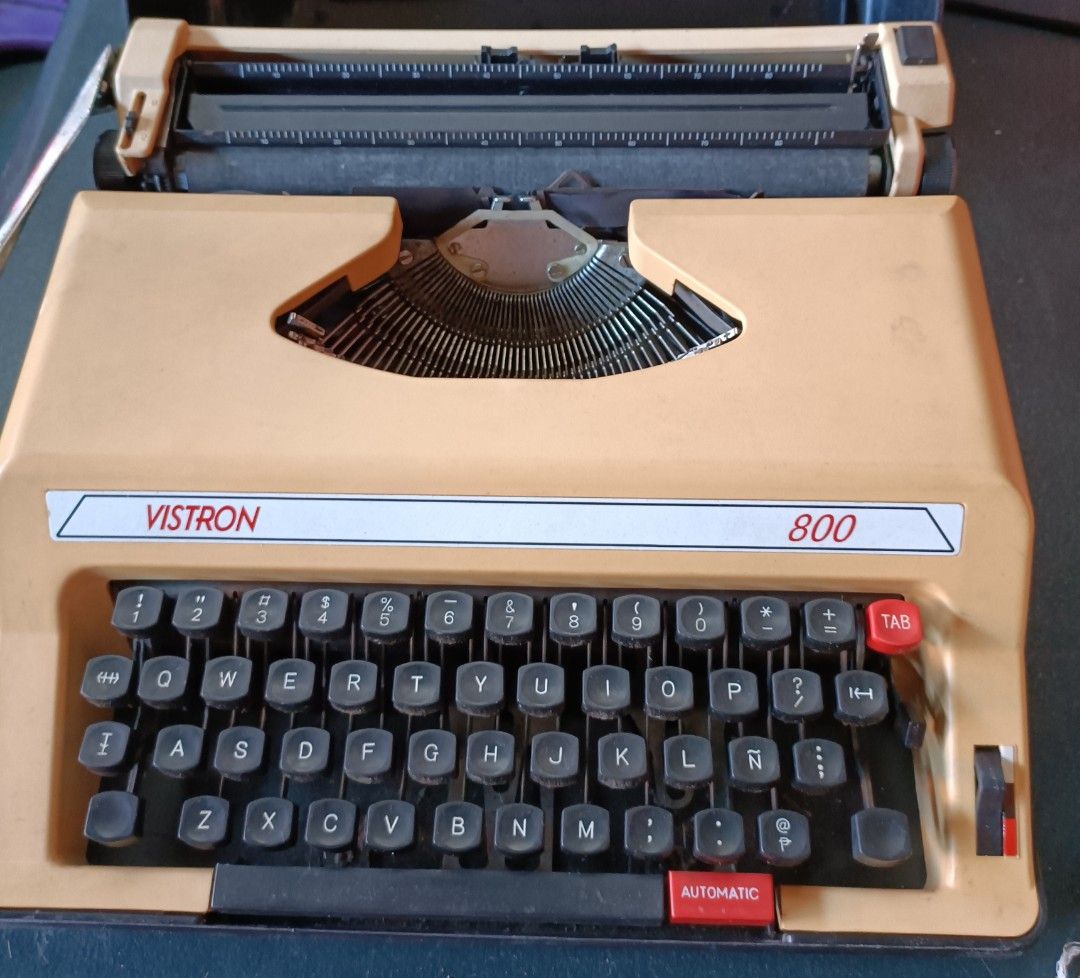 Vintage Vistron 800 Typewriter with Case (Category: Office & Business Technology) located in Imus. Submitted by lovecruzat (Listing ID 1427638150, Image 1). Description: Vintage Vistron 800 typewriter with a protective case. Features a full keyboard layout with standard keys, including a tab and automatic return function. The typewriter has a beige body with black keys and a silver carriage. Includes a black carrying case for storage and transpor