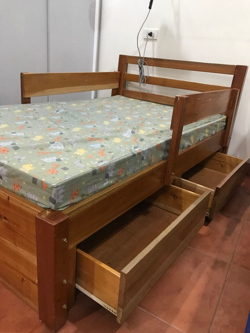 Boy's Wooden Bed Frame with Drawers (Category: Bed Frames & Mattresses) located in Quezon City. Submitted by armicg (Listing ID 1427669375, Image 1). Description: Wooden bed frame with two built-in drawers. Features a mattress with a colorful animal print. The bed frame has a headboard and side rails. The drawers provide convenient storage space. Made of mahogany wood, size: L5ft. W3ft. H1.2ft.