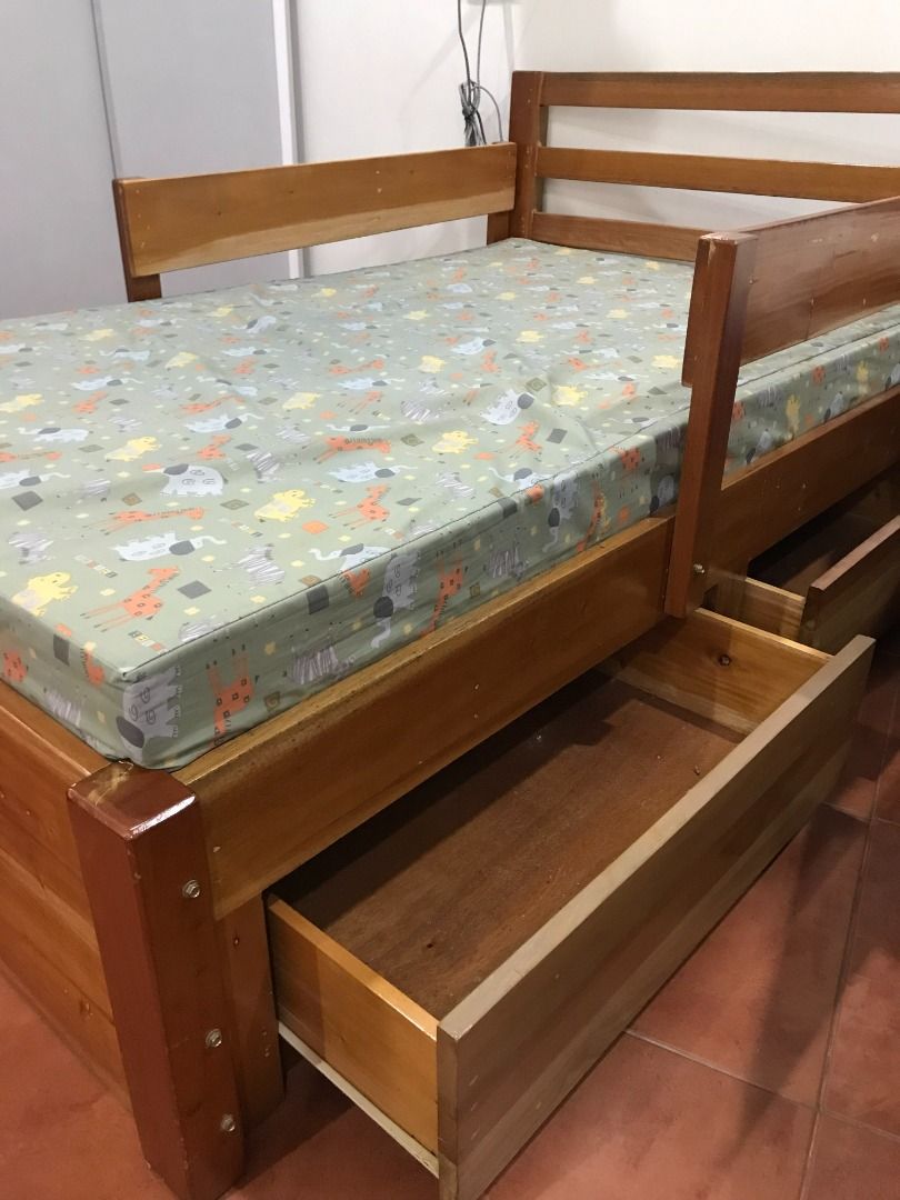Boy's Wooden Bed Frame with Drawers (Category: Bed Frames & Mattresses) located in Quezon City. Submitted by armicg (Listing ID 1427669375, Image 3). Description: Wooden bed frame with two built-in drawers. Features a mattress with a colorful animal print. The bed frame has a headboard and side rails. The drawers provide convenient storage space. Made of mahogany wood, size: L5ft. W3ft. H1.2ft.