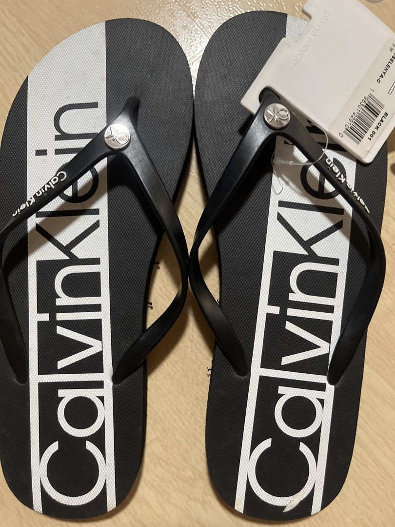 Calvin Klein Flip-flops Black (Category: Slippers and slides) located in Pasig City. Submitted by jundbaptist21 (Listing ID 1427696496, Image 1). Description: Authentic Calvin Klein flip-flops in black. Features the Calvin Klein logo in white on the footbed. Includes the original tag. The flip-flops have a black strap and a textured sole for grip. Size 9 From U.S.