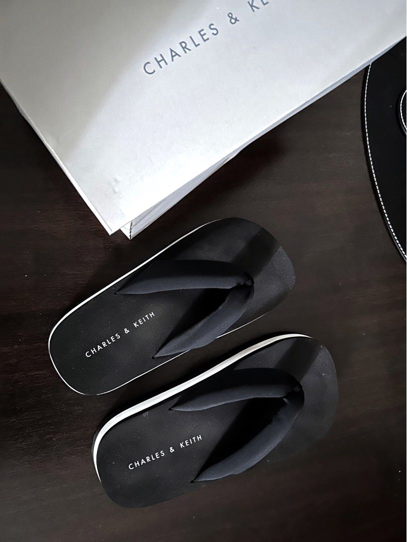Charles & Keith Flip-flops (Category: Slippers and slides) located in Quezon City. Submitted by spatio (Listing ID 1408180499, Image 1). Description: - Black Charles & Keith flip-flops - Black footbed with brand name - Black straps - Wavy sole pattern - Comes with original box.