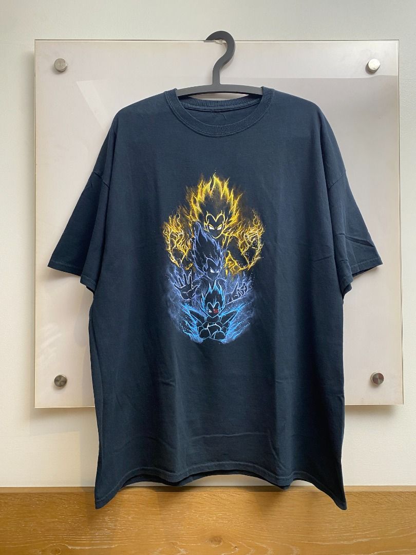 Dragon Ball Z Vegeta Graphic Tee (Category: Tshirts & Polo Shirts ) located in Pasig City. Submitted by greatestpickup (Listing ID 1427690615, Image 1). Description: Black t-shirt features a vibrant graphic of Vegeta in various Super Saiyan forms. The design showcases Vegeta with yellow and blue energy effects. The shirt has a classic crew neck design. dbz trio vegeta 25x30 2000.