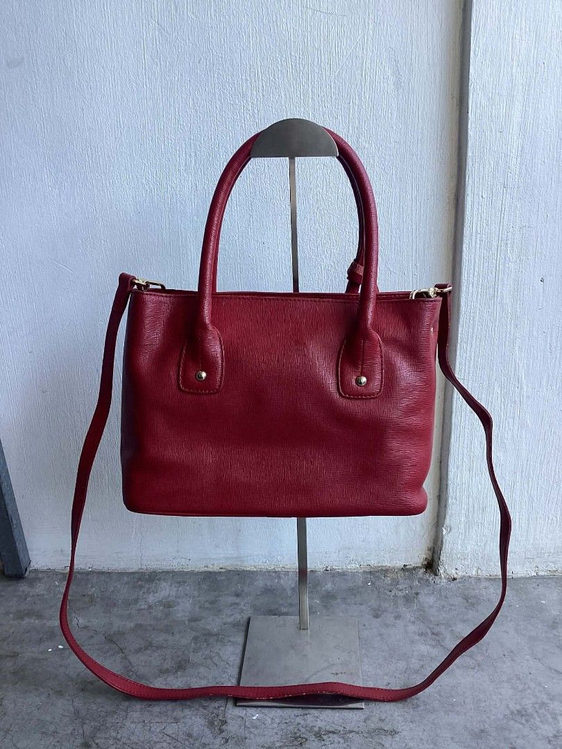 Furla Red Wine Leather Satchel (Category: Luxury Bags & Wallets) located in Cavite. Submitted by benta_bounce (Listing ID 1427698586, Image 3). Description: Furla handbag is made of red leather. It features a top handle and a detachable shoulder strap. The interior has a zipper pocket and a Furla label. The bag has gold-tone hardware and protective feet on the bottom. The Furla logo is visible on the front. Measurements: Width: 34cm Height: 19.5c
