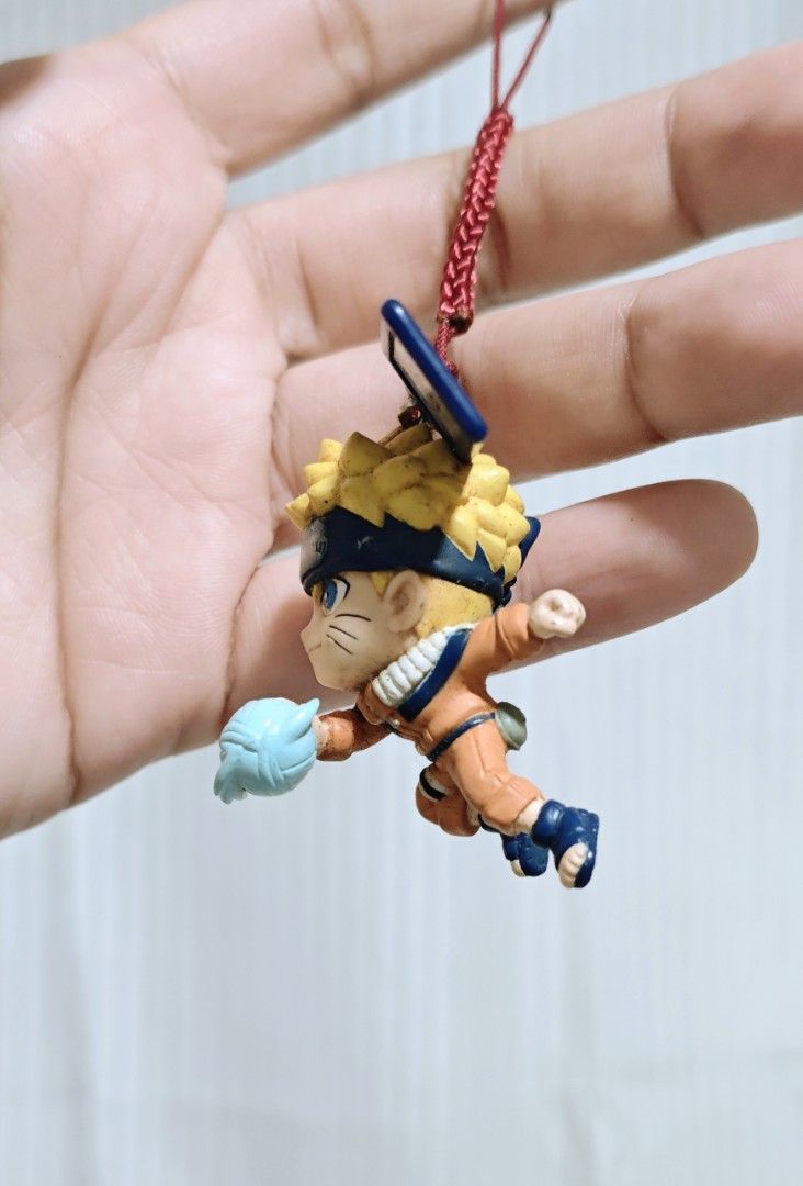 Naruto Shippuden Keychain (Category: Character Goods) located in Manila. Submitted by yourfavoritethings7 (Listing ID 1427640341, Image 2). Description: Naruto Shippuden keychain features Naruto in a dynamic pose, holding a Rasengan. It includes a red string for easy attachment. The keychain also has a small metal tag with a leaf symbol. Perfect for any Naruto fan to add to their collection or use as a bag charm..