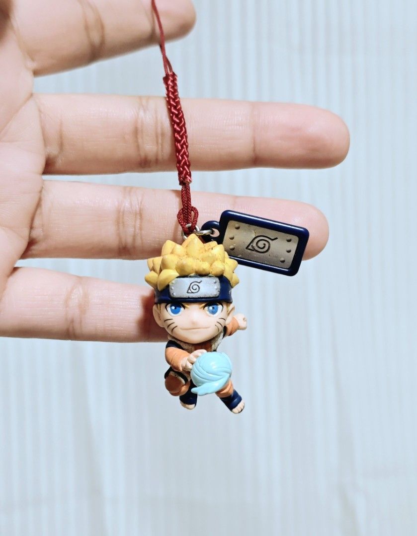 Naruto Shippuden Keychain (Category: Character Goods) located in Manila. Submitted by yourfavoritethings7 (Listing ID 1427640341, Image 1). Description: Naruto Shippuden keychain features Naruto in a dynamic pose, holding a Rasengan. It includes a red string for easy attachment. The keychain also has a small metal tag with a leaf symbol. Perfect for any Naruto fan to add to their collection or use as a bag charm..