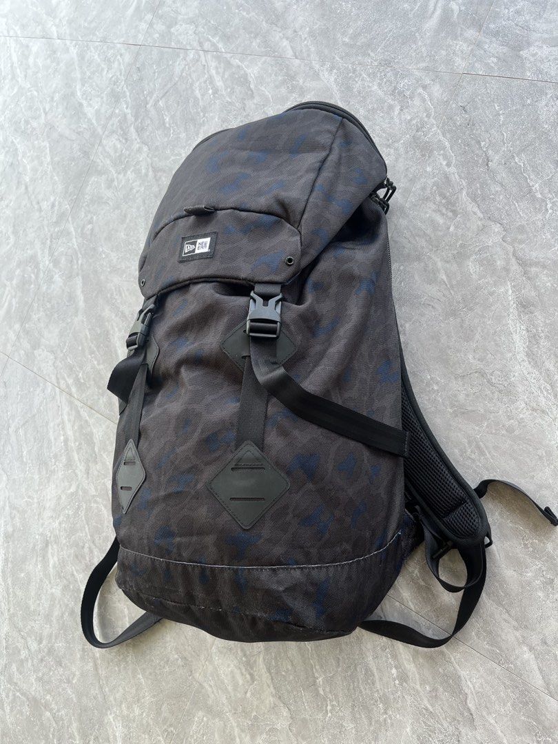 New Era Camo Backpack (Category: Backpacks) located in Dagami. Submitted by donsthrift (Listing ID 1427673603, Image 3). Description: New Era backpack features a camouflage pattern. It has adjustable shoulder straps, multiple compartments, and a top handle. The backpack includes a flap closure with buckles and a padded back panel for comfort. It also has the New Era logo on the front and back..