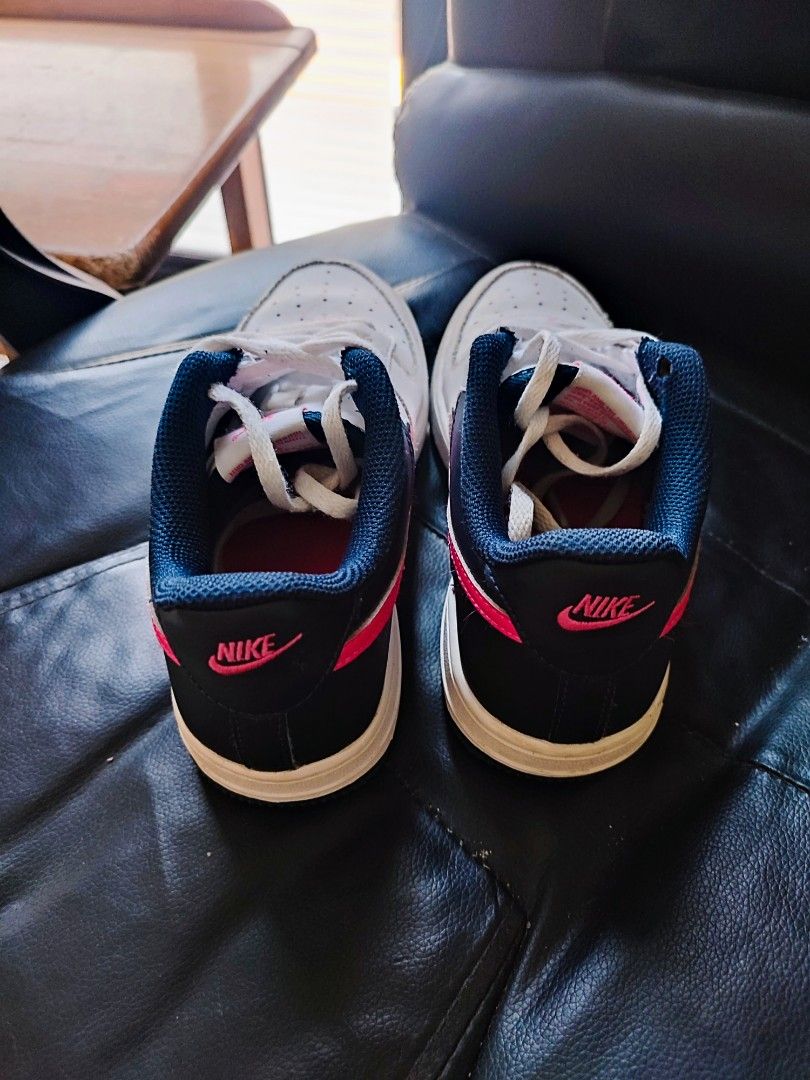 Original Nike Air Force 1 Low White Pink (Category: Babies & Kids Fashion) located in Quezon City. Submitted by PaidTY (Listing ID 1427680487, Image 2). Description: Nike Air Force 1 Low sneakers in white with pink accents. Features a white leather upper with a pink swoosh and a navy blue collar. The Nike logo is visible on the heel and tongue. Includes white laces. Size: US 3, 22 cm rfs: outgrown needs cleaning only.