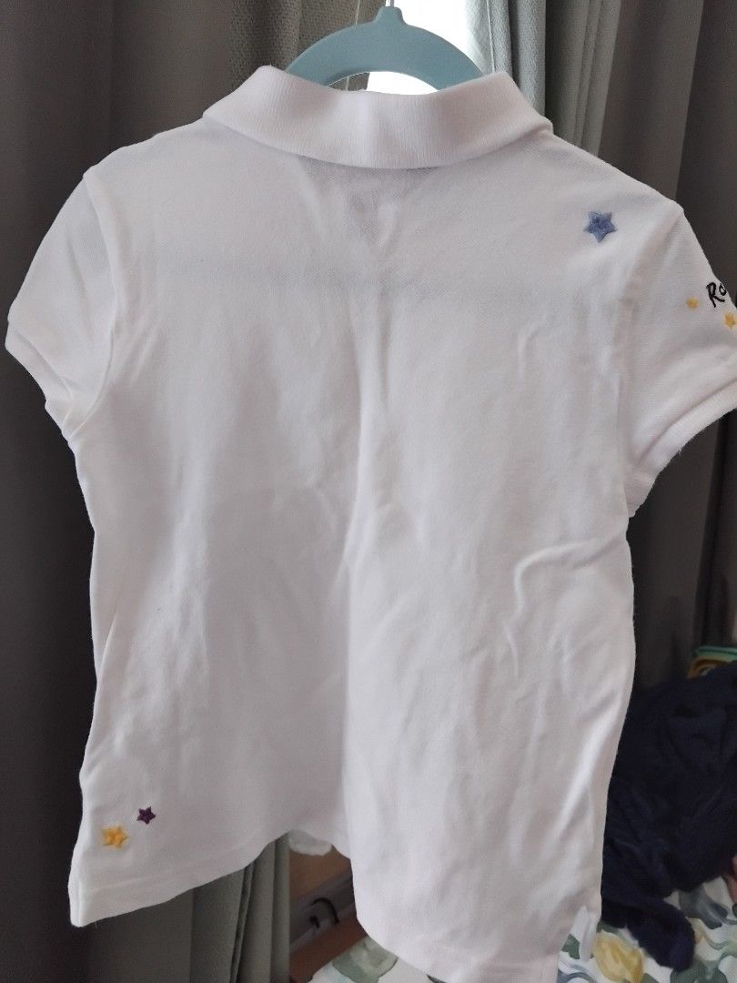 Ralph Lauren White Polo Shirt (Category: Babies & Kids Fashion) located in Manila. Submitted by leontheexplorer (Listing ID 1427697644, Image 2). Description: - White polo shirt from Ralph Lauren - Features a small pink logo on the chest and embroidered details on the sleeve - Includes a heart design with "RL" on the side - Fits up to 6 yrs old depending on the body frame - Has a classic polo collar and button-up front - The shirt is short-sleeve