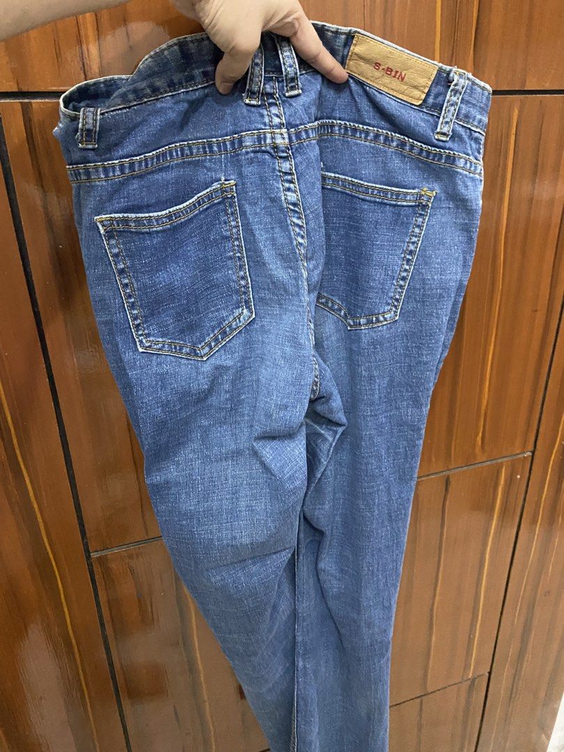 S-BIN Skinny Jeans (Category: Jeans) located in Pateros City. Submitted by downsizin (Listing ID 1427712525, Image 3). Description: Blue jeans with a classic five-pocket design. Features a button and zipper closure. The jeans have a straight leg cut with a slightly frayed hem. The brand name "S-BIN" is visible on the back of the jeans. The jeans have yellow stitching..