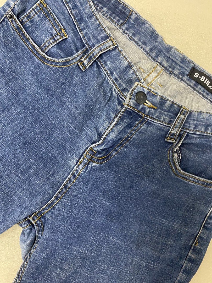 S-BIN Skinny Jeans (Category: Jeans) located in Pateros City. Submitted by downsizin (Listing ID 1427712525, Image 1). Description: Blue jeans with a classic five-pocket design. Features a button and zipper closure. The jeans have a straight leg cut with a slightly frayed hem. The brand name "S-BIN" is visible on the back of the jeans. The jeans have yellow stitching..