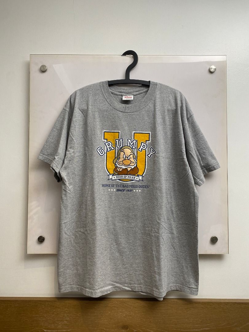 Vintage 90's Disney Grumpy T-shirt (Category: Tshirts & Polo Shirts ) located in Pasig City. Submitted by greatestpickup (Listing ID 1427669887, Image 1). Description: Gray t-shirt featuring Grumpy from Disney's Snow White. The design includes the word "GRUMPY" in a yellow and blue font, along with an image of Grumpy. It also has the text "HOME OF THE BAD MOOD DUDES" and "SINCE 1937". disney grumpy dean of mean 24x31 1000.