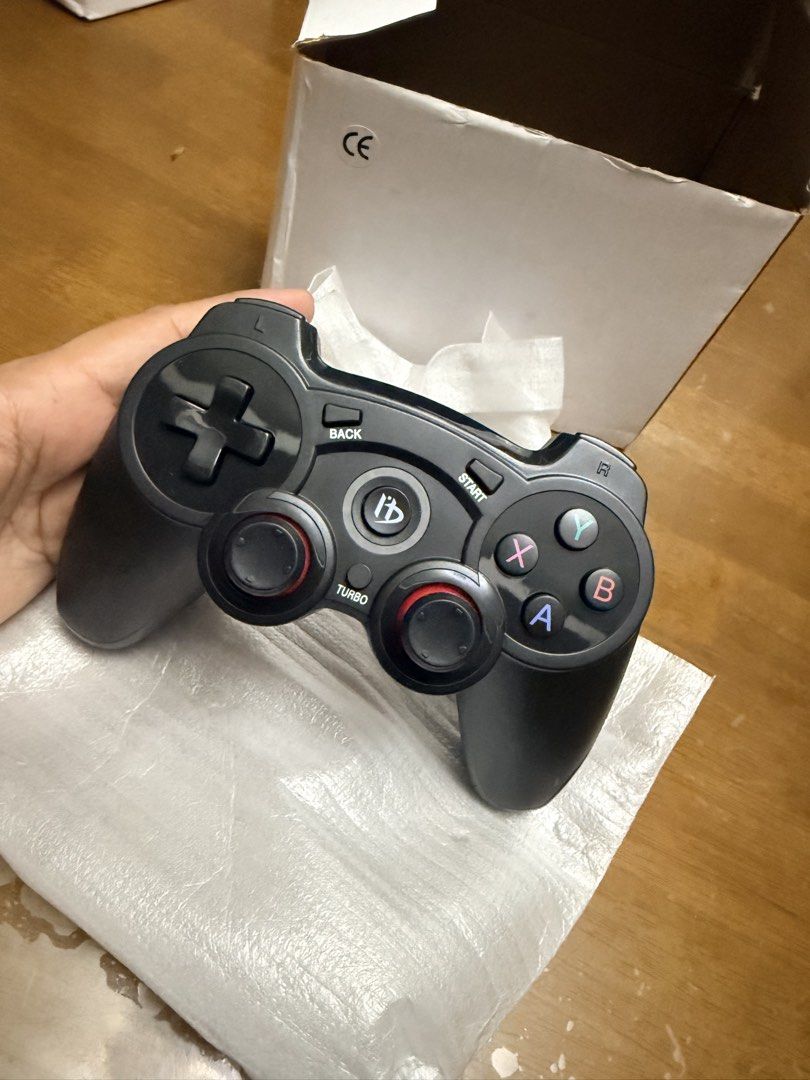 Wireless Game Controller (Category: Controllers) located in Pilar. Submitted by faveanyshop (Listing ID 1427673379, Image 1). Description: Wireless game controller with a black design. Features include a D-pad, action buttons (X, Y, A, B), and dual analog sticks. Includes a USB receiver and a charging port. Comes with its original box..