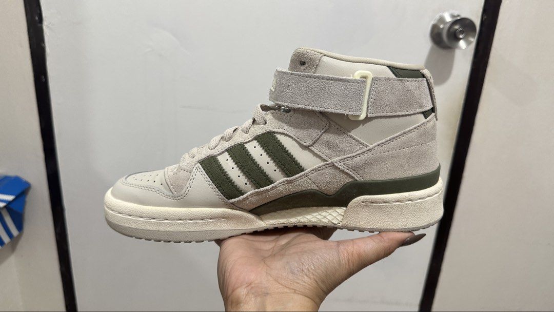 Adidas Forum Mid W GY4869 (Category: Sneakers) located in Antipolo. Submitted by janeymeee760 (Listing ID 1427874148, Image 2). Description: Adidas Forum Mid W sneakers in a neutral colorway with olive green accents. Features a high-top design with a velcro strap. The shoes are in their original box. Size US 9, UK 7.5, EUR 41 1/3, and CHN 260. The original price tag shows S$149.00. Bought in SG. Used once. .