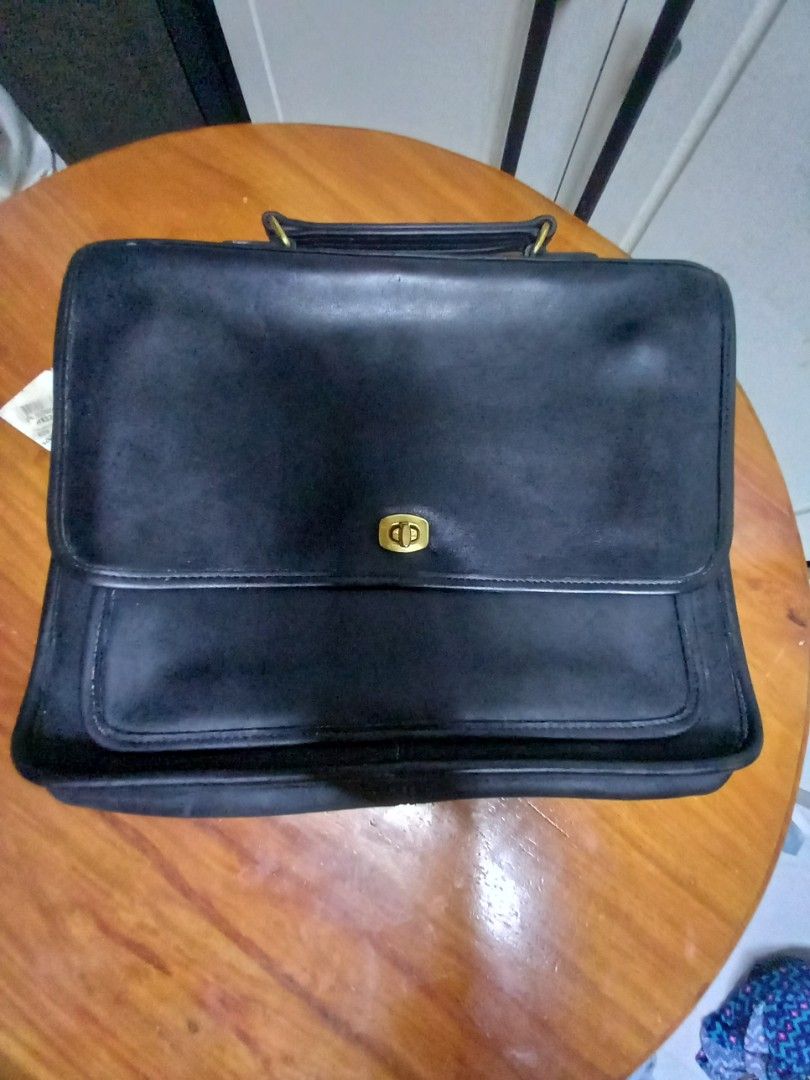 Coach Black Leather Briefcase (Category: Briefcases) located in Tuguegarao City. Submitted by zenphoenix-7ad615 (Listing ID 1427872018, Image 3). Description: Classic Coach briefcase in black leather. Features a flap closure with a gold-tone turn lock. Includes a top handle and a front pocket. The interior has a zipper pocket and a Coach logo. The tag shows the style number 9850. A timeless and stylish accessory for everyday use. 13.5 by 10 inche