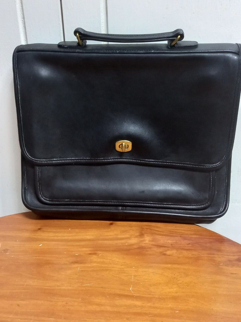 Coach Black Leather Briefcase (Category: Briefcases) located in Tuguegarao City. Submitted by zenphoenix-7ad615 (Listing ID 1427872018, Image 2). Description: Classic Coach briefcase in black leather. Features a flap closure with a gold-tone turn lock. Includes a top handle and a front pocket. The interior has a zipper pocket and a Coach logo. The tag shows the style number 9850. A timeless and stylish accessory for everyday use. 13.5 by 10 inche