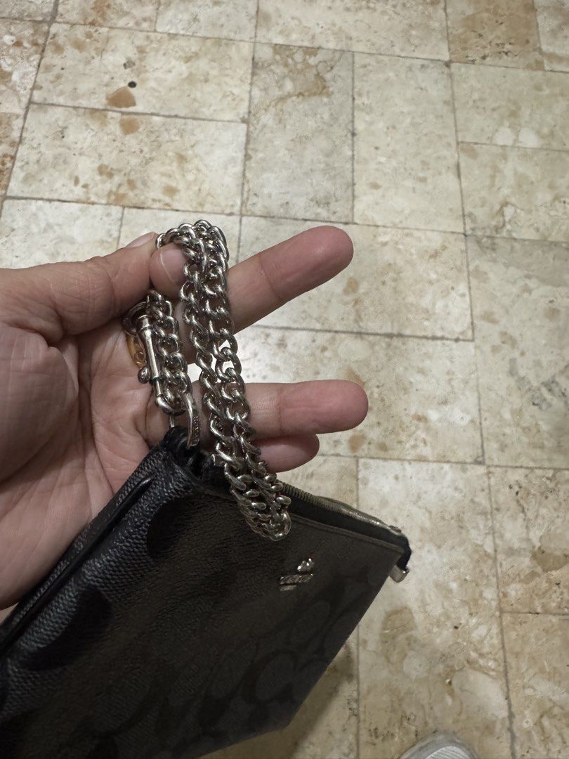 Coach Signature Clutch with Chain (Category: Luxury Bags & Wallets) located in San Juan City. Submitted by idecluttersj (Listing ID 1427906152, Image 2). Description: Black Coach clutch with signature pattern. Features a silver chain strap and a zip closure. The Coach logo is visible on the front of the clutch..