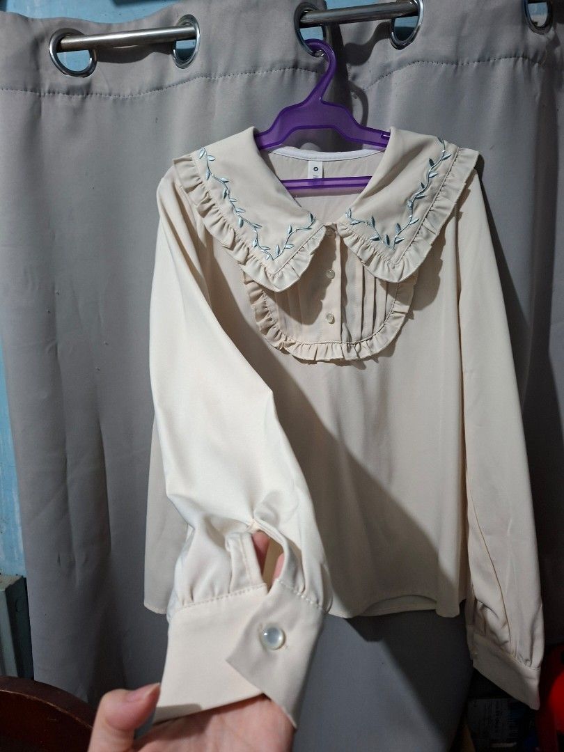 Cream-colored Blouse with Embroidered Sleeves (Category: Blouses) located in Manila. Submitted by eli959 (Listing ID 1427868620, Image 2). Description: Cream-colored blouse with long sleeves. Features delicate blue embroidery along the cuffs and collar. The collar has a ruffled design. Includes button closures on the cuffs and at the neckline..