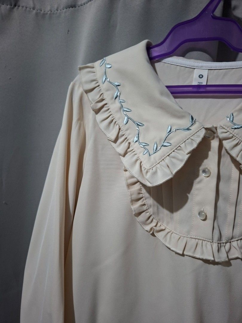 Cream-colored Blouse with Embroidered Sleeves (Category: Blouses) located in Manila. Submitted by eli959 (Listing ID 1427868620, Image 1). Description: Cream-colored blouse with long sleeves. Features delicate blue embroidery along the cuffs and collar. The collar has a ruffled design. Includes button closures on the cuffs and at the neckline..