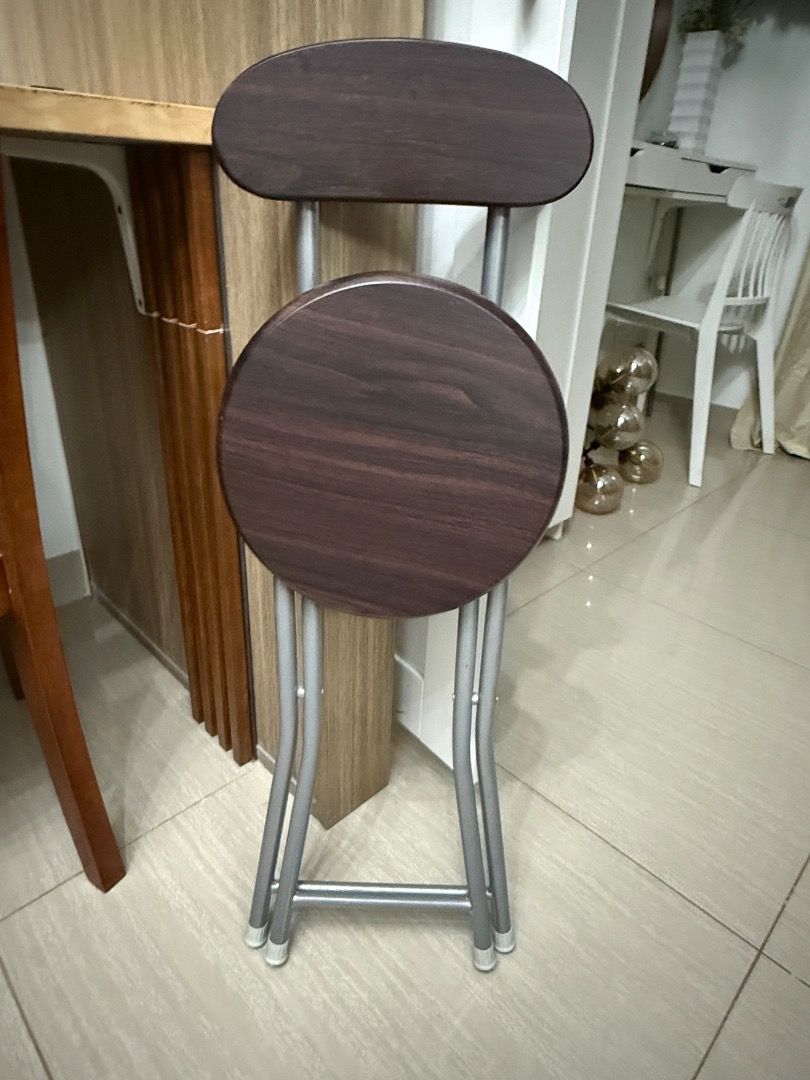 Folding Chair with Backrest (Category: Chairs) located in Tiaong. Submitted by bopeep23 (Listing ID 1427845043, Image 2). Description: Folding chair features a dark brown wooden seat and backrest, supported by a silver metal frame. It has a round seat and a backrest for added comfort. The chair is designed to fold for easy storage and portability. It's a practical seating solution for various settings..