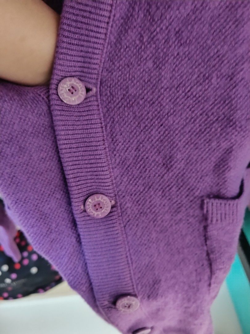 Lacoste Purple Cardigan (Category: Coats, Jackets and Outerwear) located in Trece Martires City. Submitted by declutterbyedi (Listing ID 1427791050, Image 3). Description: Purple cardigan from Lacoste. It features a V-neck, button closure, and two front pockets. The Lacoste logo is visible on the chest. The label indicates it is made in France. The buttons have the Lacoste logo on them. The cardigan is a solid purple color..