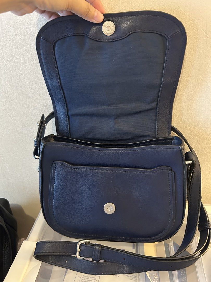 Marc Jacobs Navy Blue Crossbody Bag (Category: Luxury Bags & Wallets) located in Mandaluyong City. Submitted by geri3373 (Listing ID 1427855990, Image 2). Description: Navy blue crossbody bag by Marc Jacobs. Features a flap closure with a magnetic snap. The interior includes a zippered pocket and a slip pocket. The bag has a long adjustable strap. The hardware is silver.