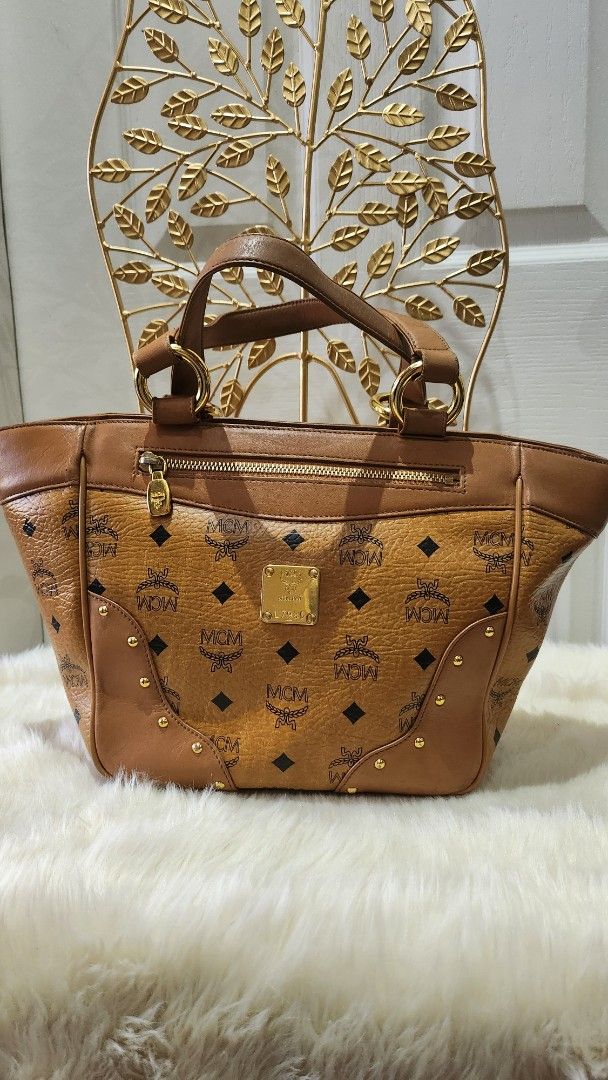 MCM handbag (Category: Luxury Bags & Wallets) located in Cavite. Submitted by geturs (Listing ID 1427803710, Image 1). Description: Authentic MCM Visetos tote bag. Features the iconic MCM logo pattern. The bag has a top handle and a zipper closure. The exterior is brown with gold-tone hardware. A gold MCM logo plate is visible on the front..