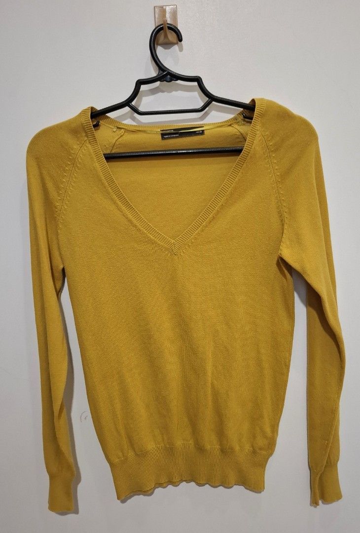 Zara Mustard Yellow V-Neck Sweater (Category: Coats, Jackets and Outerwear) located in Imus. Submitted by maggieforce (Listing ID 1427848159, Image 1). Description: Mustard yellow sweater with a V-neck design. Features long sleeves and a ribbed hem. The sweater is hanging on a black hanger. The overall design is simple and classic..