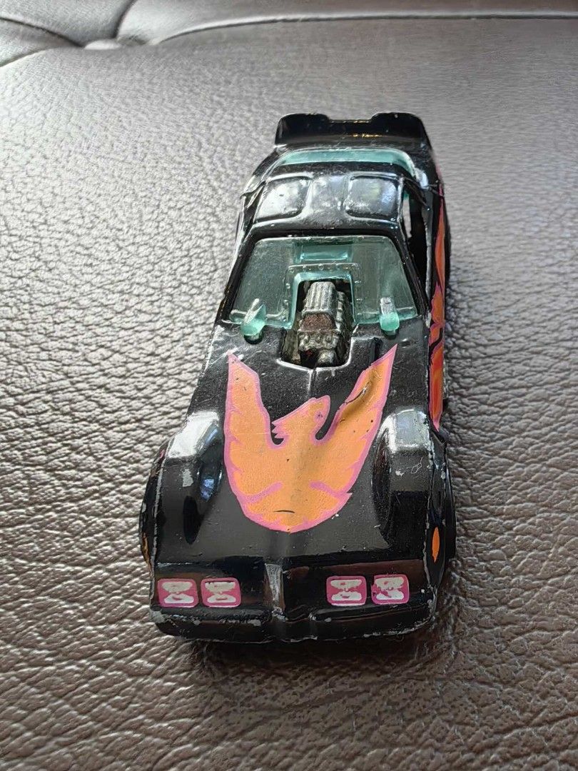 1977 Hot Wheels Black Firebird Funny Car (Category: Vehicle & Diecast Models) located in Quezon City. Submitted by daned05 (Listing ID 1427996475, Image 1). Description: 1977 Hot Wheels Black Firebird Funny Car Vintage Hot Wheels toy car. Features a black body with a flame design in orange and pink. The car has a visible engine and silver wheels. The car's body is separated from the chassis. The car has some wear and tear. Selling as is, where is