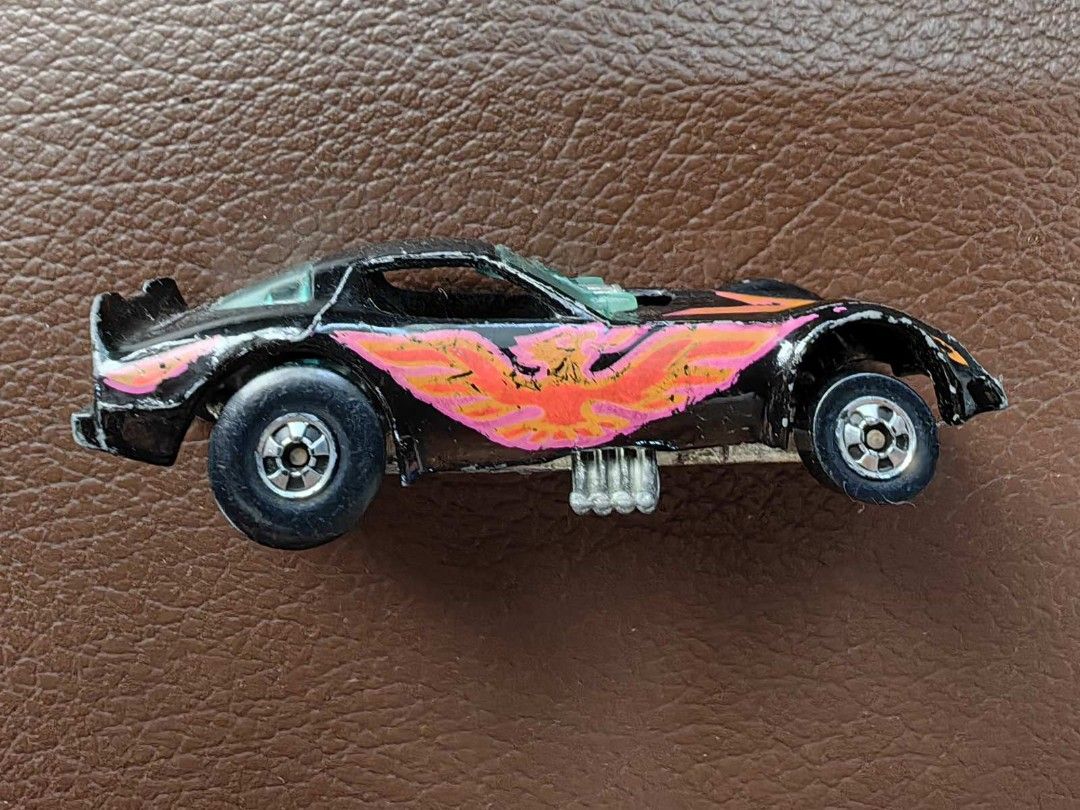 1977 Hot Wheels Black Firebird Funny Car (Category: Vehicle & Diecast Models) located in Quezon City. Submitted by daned05 (Listing ID 1427996475, Image 2). Description: 1977 Hot Wheels Black Firebird Funny Car Vintage Hot Wheels toy car. Features a black body with a flame design in orange and pink. The car has a visible engine and silver wheels. The car's body is separated from the chassis. The car has some wear and tear. Selling as is, where is