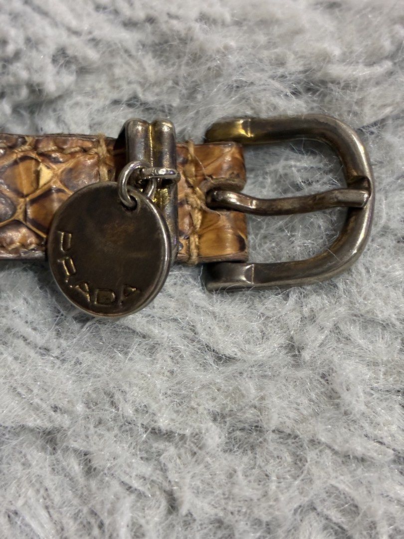 Authentic Prada Snakeskin Bracelet (Category: Luxury Accessories) located in Manila. Submitted by cellymeji060371 (Listing ID 1427964063, Image 2). Description: Authentic Prada bracelet featuring a snakeskin design. The bracelet has a silver buckle and a Prada logo charm. The interior of the bracelet is black leather with the Prada logo embossed. The snakeskin shows some wear and tear. A stylish accessory for any outfit. Has leather cracks, thus 