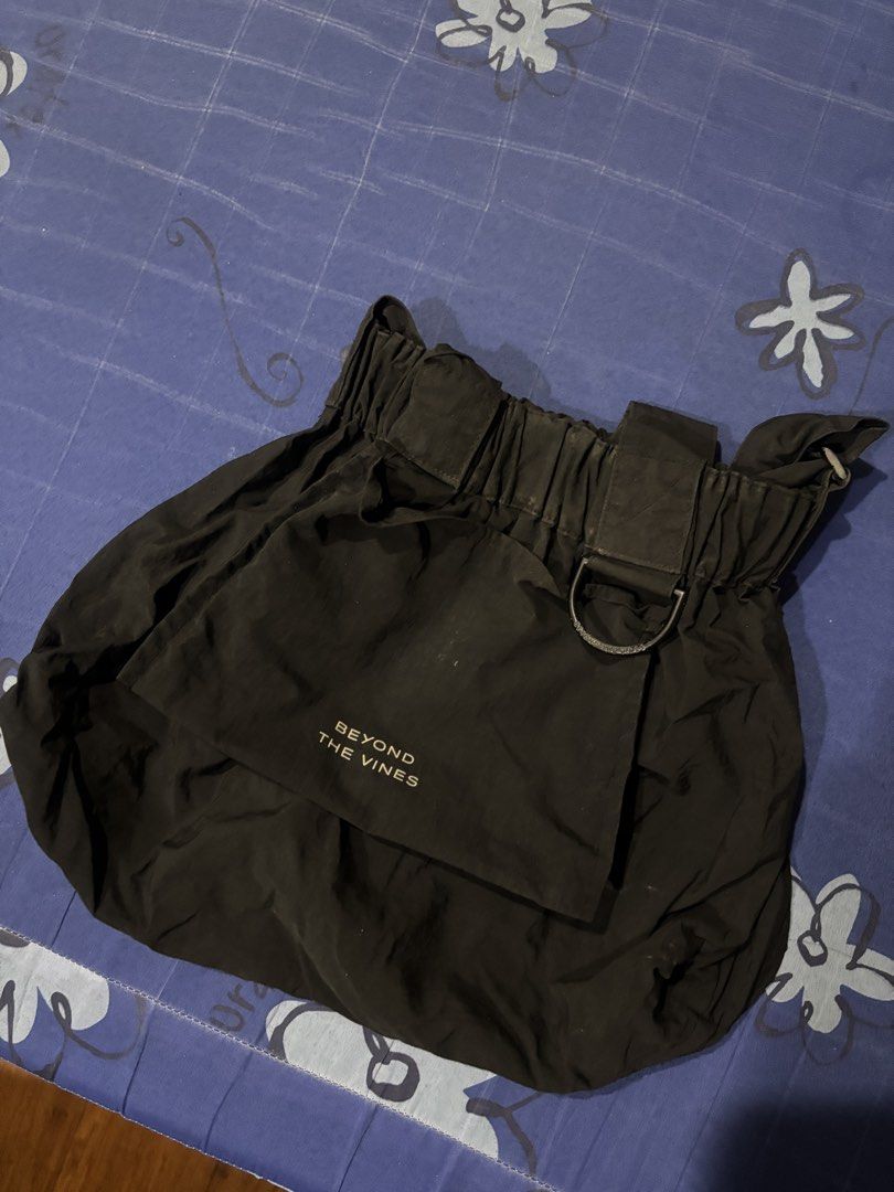Beyond The Vines Dumpling Bag (Category: Cross-body Bags) located in Quezon City. Submitted by b_declutter (Listing ID 1428041509, Image 1). Description: Black Beyond The Vines Dumpling Bag. Features a main compartment with a drawstring closure. Includes a small front pocket with the brand name. Comes with a detachable shoulder strap. The bag has a unique, rounded shape. The strap has a metal buckle..