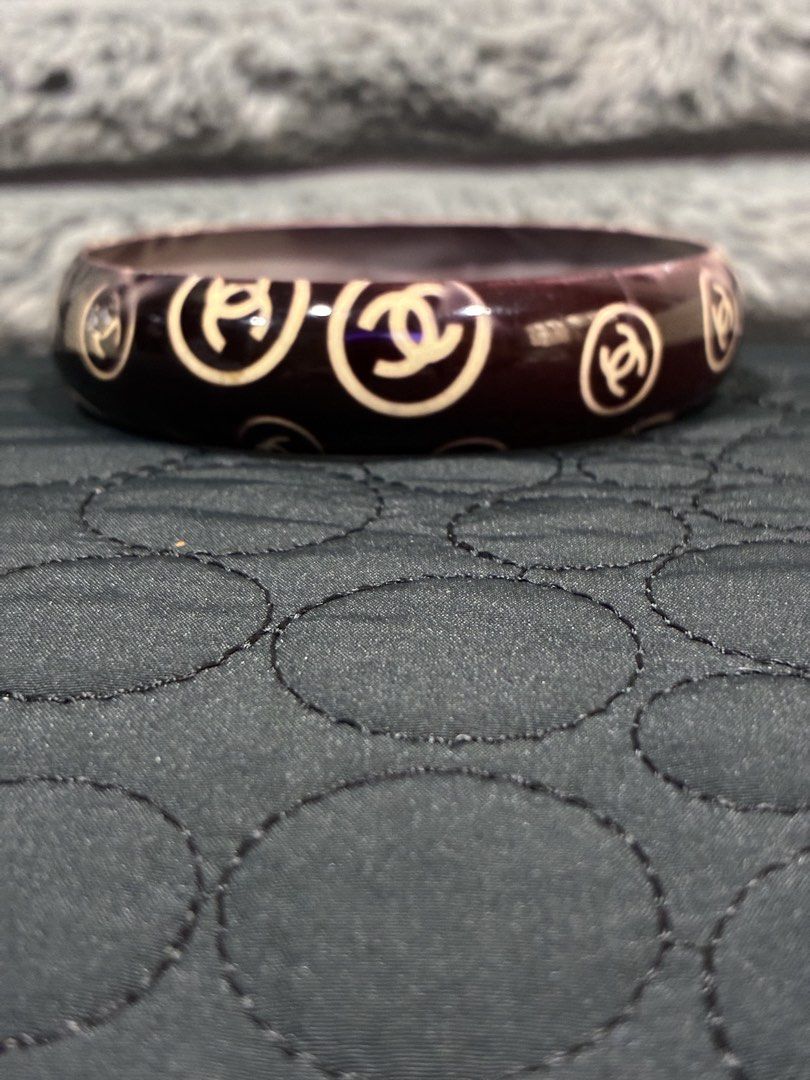 Chanel Bangle Bracelet (Category: Luxury Accessories) located in Manila. Submitted by cellymeji060371 (Listing ID 1427962784, Image 2). Description: Elegant bangle bracelet featuring the iconic Chanel logo. The bracelet has a dark burgundy base with the Chanel logo in a contrasting cream color. It is a wide, rounded design. The bracelet is shown worn on a wrist..