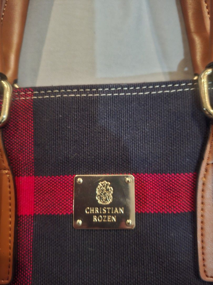 Christian Rozen Tote Bag with Shoulder Strap (Category: Tote Bags) located in Las Pinas. Submitted by bethany1965 (Listing ID 1427991539, Image 3). Description: Never been used, gifted to me last Christmas. Stylish tote bag by Christian Rozen. Features a navy blue fabric with red and white stripes. It has brown leather handles and a detachable shoulder strap. The bag includes a front pocket and a zippered main compartment. The Christian Rozen log