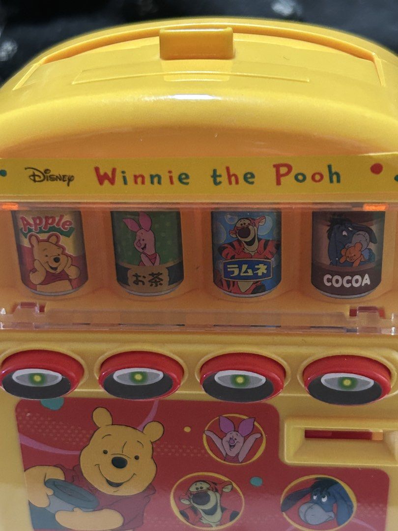 Disney Winnie the Pooh Vending Machine Toy (Category: Character Goods) located in Angeles City. Submitted by zyeplustradings (Listing ID 1428094865, Image 3). Description: Yellow Disney Winnie the Pooh vending machine toy. It features four drink options: Apple, Tea, Ramune, and Cocoa. The toy has buttons and illustrations of Winnie the Pooh and his friends..
