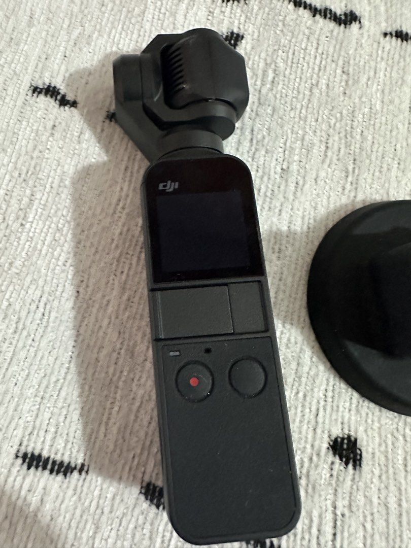 DJI Osmo Pocket 1 (Category: Cameras) located in Las Pinas. Submitted by truecrystal-76d40f (Listing ID 1428002901, Image 3). Description: DJI Osmo Pocket camera with accessories. Includes the camera itself, a protective case, and a base. The camera has a small screen and two buttons. The camera is black..