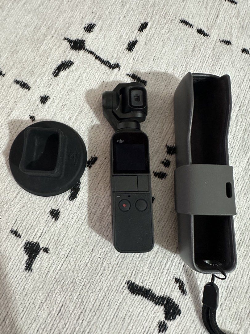 DJI Osmo Pocket 1 (Category: Cameras) located in Las Pinas. Submitted by truecrystal-76d40f (Listing ID 1428002901, Image 1). Description: DJI Osmo Pocket camera with accessories. Includes the camera itself, a protective case, and a base. The camera has a small screen and two buttons. The camera is black..