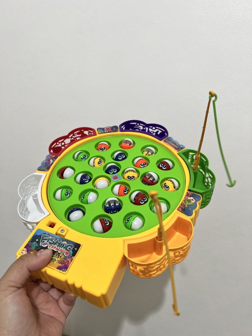 Fishing Game Toy (Category: Kids Toys) located in Cavite. Submitted by nlp_preloved (Listing ID 1427947185, Image 1). Description: Fun fishing game toy for kids. Features a rotating board with colorful fish and fishing rods. Includes a yellow base with fish storage and a button. Great for developing hand-eye coordination and providing hours of entertainment. Perfect for young children..